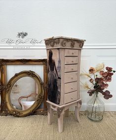 an old dresser is next to a vase with flowers in it and a photo frame