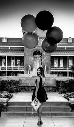 a woman standing in front of a building with black and white balloons