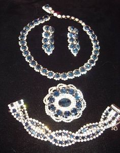 "This fabulous Kramer Suite, 4 Matching Pieces of large sapphire round stones surrounded with small rhinestones.   Adjustable necklace and  clip back Drop earrings.   The  large oval pin has a big oval sapphire stone in the center with small rhinestones surrounding, an outside raised edge of large oval  and round blue stones is finished with a double rhinestone swirling band.  A matching style  bracelet is a double row of rhinestones wit sapphire baguettes in the middle in an overlapping design, Dazzling Oval Jewelry For Evening, Dazzling Oval Evening Jewelry, Evening Diamond Jewelry Sets With 17 Jewels, Vintage Hand Set Round Jewelry, Vintage Round Hand Set Jewelry, Luxury Blue Jewelry With Rhinestones, Oval Costume Jewelry For Parties, Luxury Blue Rhinestone Jewelry, Dazzling Rhinestone Jewelry Sets For Formal Occasions