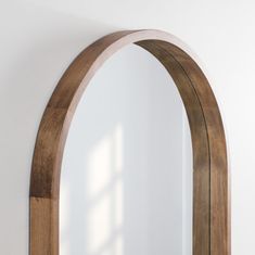 an arched wooden mirror mounted to the side of a wall