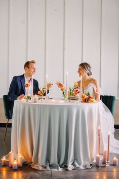 a man and woman sitting at a table with candles in front of them on their wedding day