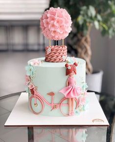 a cake decorated with pink flowers and a girl on a bike