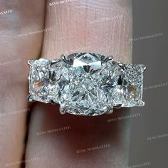 a diamond ring with three stones on it's side, in the palm of someone's hand