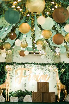 a stage set up with paper lanterns and giraffes in the center, surrounded by greenery