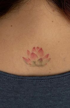 a woman's back neck with a pink flower tattoo on her left upper arm