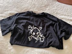 a black shirt with white skull and crossbones is laying on a bed spread