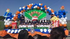 a group of people standing in front of a float with baseball players and balloons on it