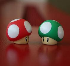 two nintendo mushroom figurines sitting on top of a red table