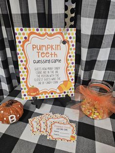 a table topped with candy and pumpkins next to a sign