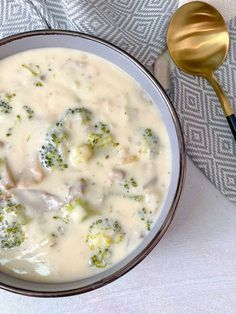 a bowl of broccoli and cheese soup next to a spoon