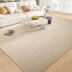 a living room with white couches and pillows on top of the rug in front of a large window