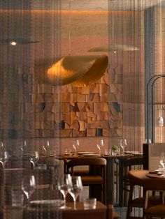 a restaurant with wooden tables and chairs in front of a decorative wall hanging from the ceiling