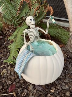 a skeleton figurine sitting on top of a potted plant in the ground