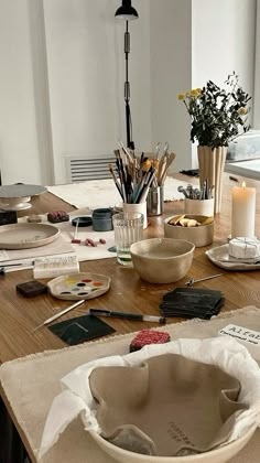 a wooden table topped with lots of crafting supplies and flowers in vases on top of it