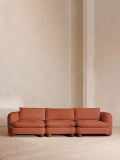 an orange couch sitting on top of a hard wood floor next to a white wall