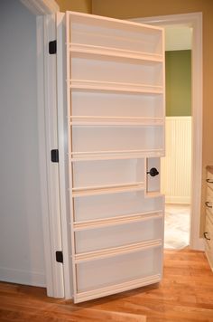 an open white refrigerator sitting on top of a hard wood floor