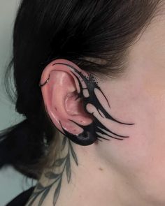 a woman's ear with black and white tattoos on it