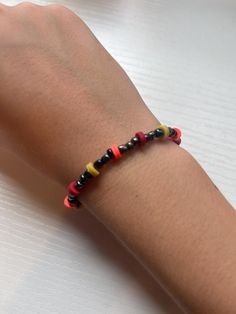 a person's arm with a bracelet made out of colorful beads on top of it