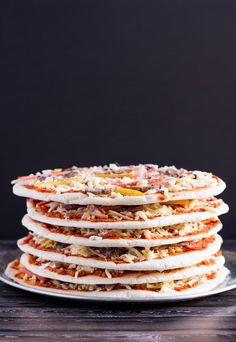 a stack of food sitting on top of a white plate next to a black wall