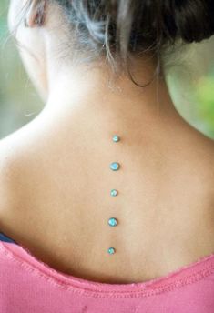 the back of a woman's neck with blue stones on it