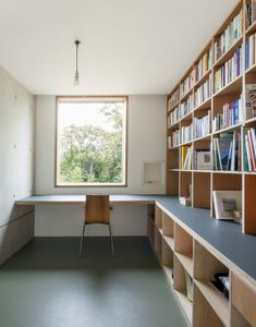 an empty room with bookshelves and a desk in front of a large window