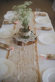 the table is set with white plates and flowers