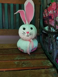 a stuffed bunny sitting on top of a wooden bench