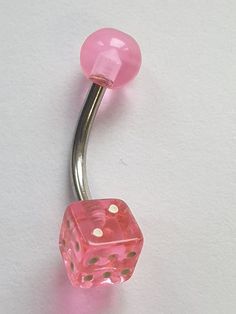 a pink dice shaped belly ring on a white background