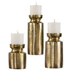 three gold candle holders with white candles in them