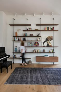 a woman is walking in front of a bookshelf with shelves on the wall