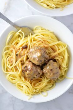 two white bowls filled with spaghetti and meatballs