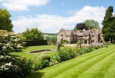 a large house sitting in the middle of a lush green field with lots of trees