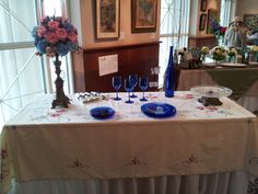 the table is set with blue glassware and flowers