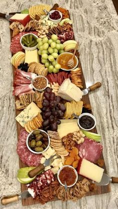 a platter filled with different types of cheeses and crackers on top of a marble counter