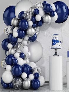 a blue and white balloon arch with silver and white balloons on the wall next to it