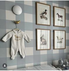 a baby's room with three pictures on the wall and a bird hanging above it