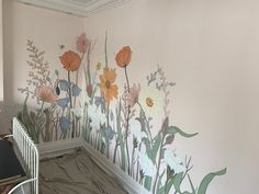 a baby's crib in front of a wall with flowers painted on it