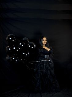 a woman in a black dress holding balloons