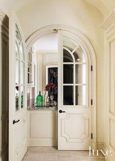 an arched doorway leading to a kitchen with marble counter tops and white walls, along with two green vases on either side