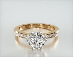 a diamond engagement ring with channel set diamonds on the band and an 18k yellow gold band