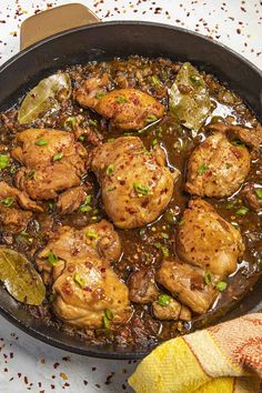 a skillet filled with meat and vegetables on top of a table