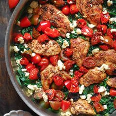 a pan filled with chicken, tomatoes and spinach