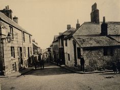 an old black and white photo of people walking down the street in front of buildings