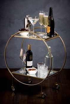 three tiered bar cart with wine glasses and bottles on it