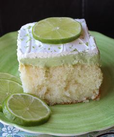 a slice of lime cake on a green plate with two lime wedges next to it