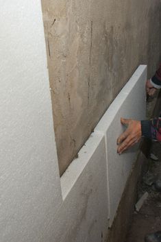 two people standing next to each other in an unfinished room with cement walls and plaster on the floor