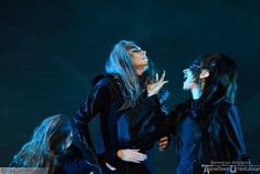 three women dressed in black standing on stage with one holding her face to the side