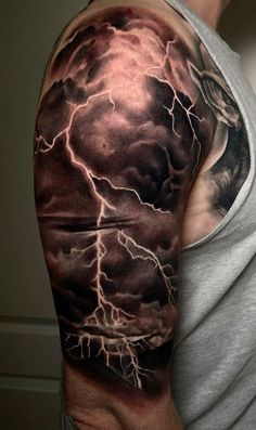 a man's arm with a storm and lightning tattoo on the left shoulder, it is