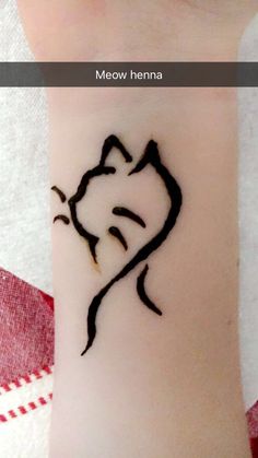 a cat tattoo on the wrist is shown in black ink, and it looks like someone has