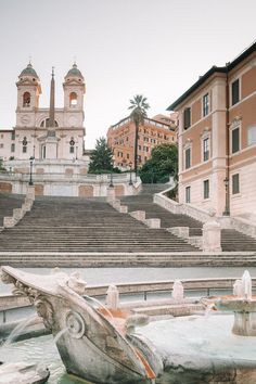 an old fountain in front of a building with steps leading up to it and a clock tower